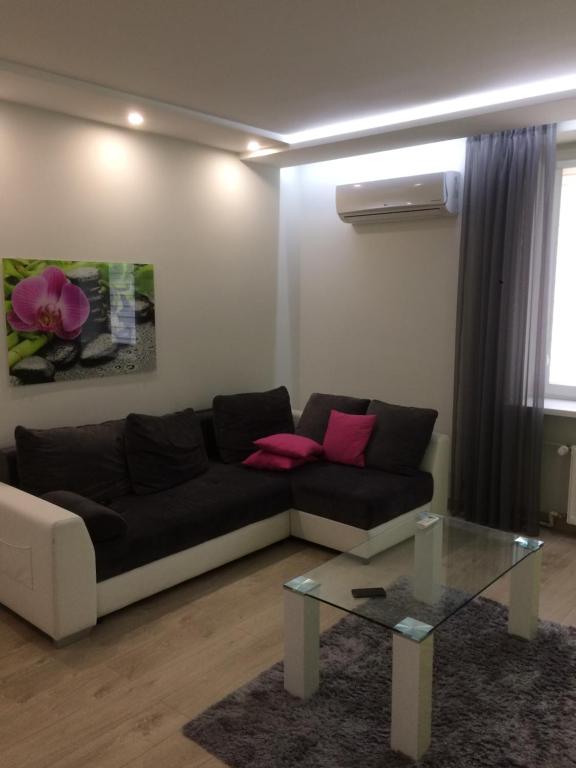 a living room with a black couch and a glass table at Nordic Apartamenty Sienkiewicza in Białystok