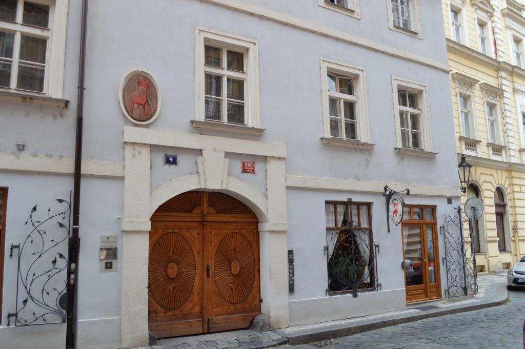 ein weißes Gebäude mit einer Uhr über einer Holztür in der Unterkunft U Cervene zidle - Red Chair Hotel in Prag