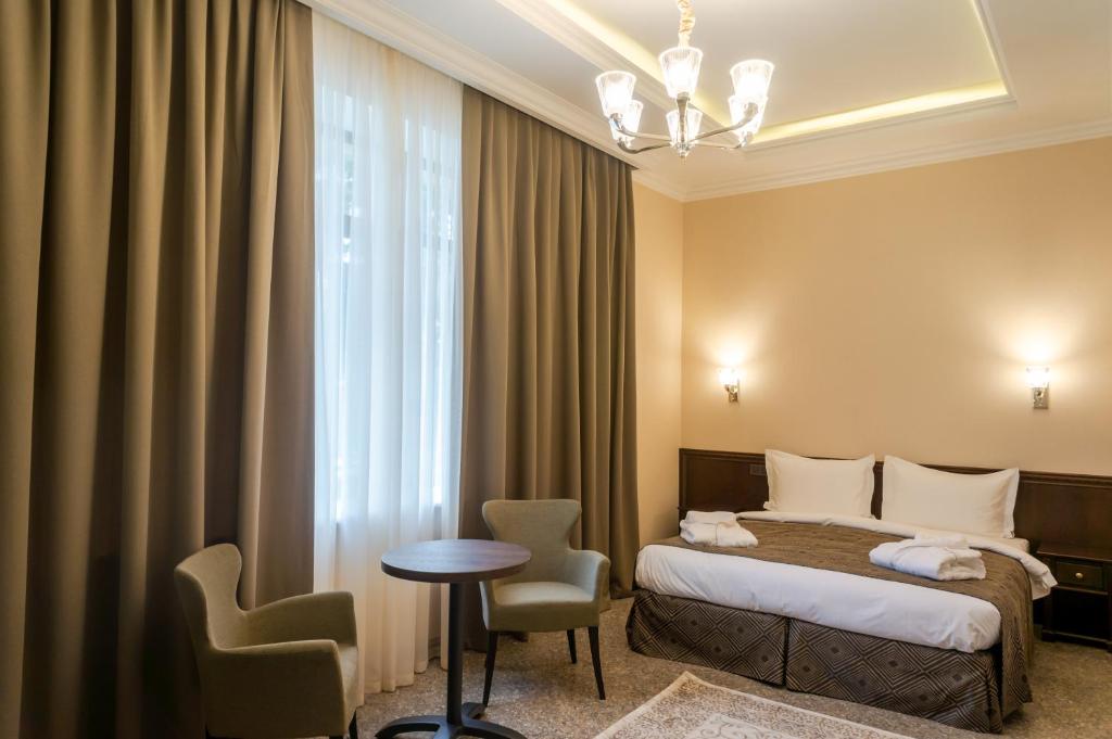 a hotel room with a bed and a table and chairs at Royal Plus Hotel in Almaty