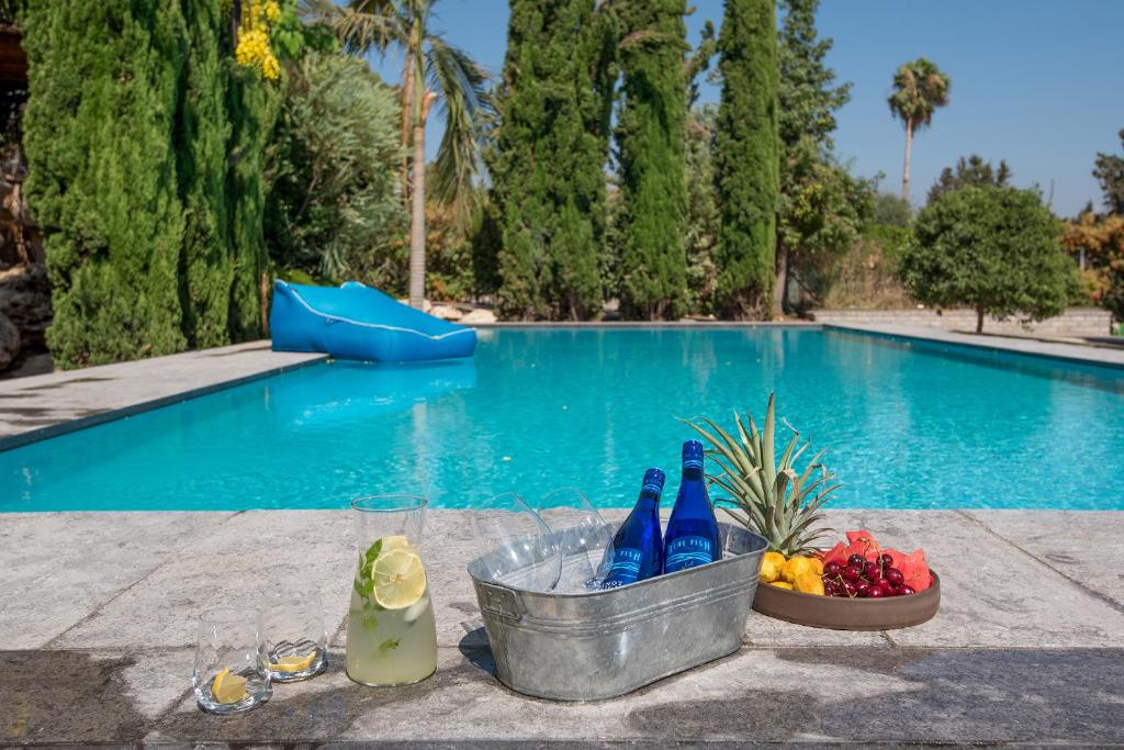 een zwembad met een fruitschaal en twee flessen bij Felina place by Shuli in Ganne Yoẖanan