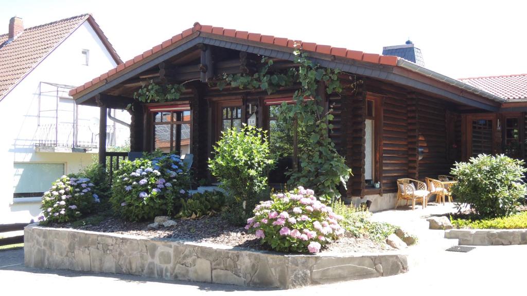 a log cabin with flowers in front of it at Ferienwohnung Blockhaus Juka in Vinningen