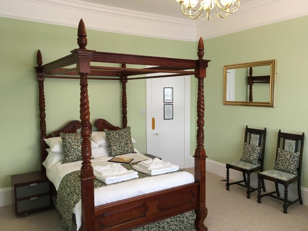 1 Schlafzimmer mit einem hölzernen Himmelbett und 2 Stühlen in der Unterkunft The Snowdon House in Shanklin