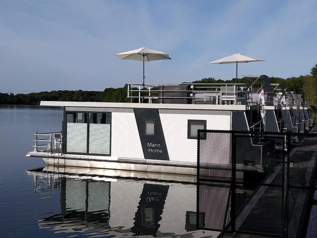 een boot is aangemeerd op het water met parasols bij Hausboot Leukermeer Well in Well