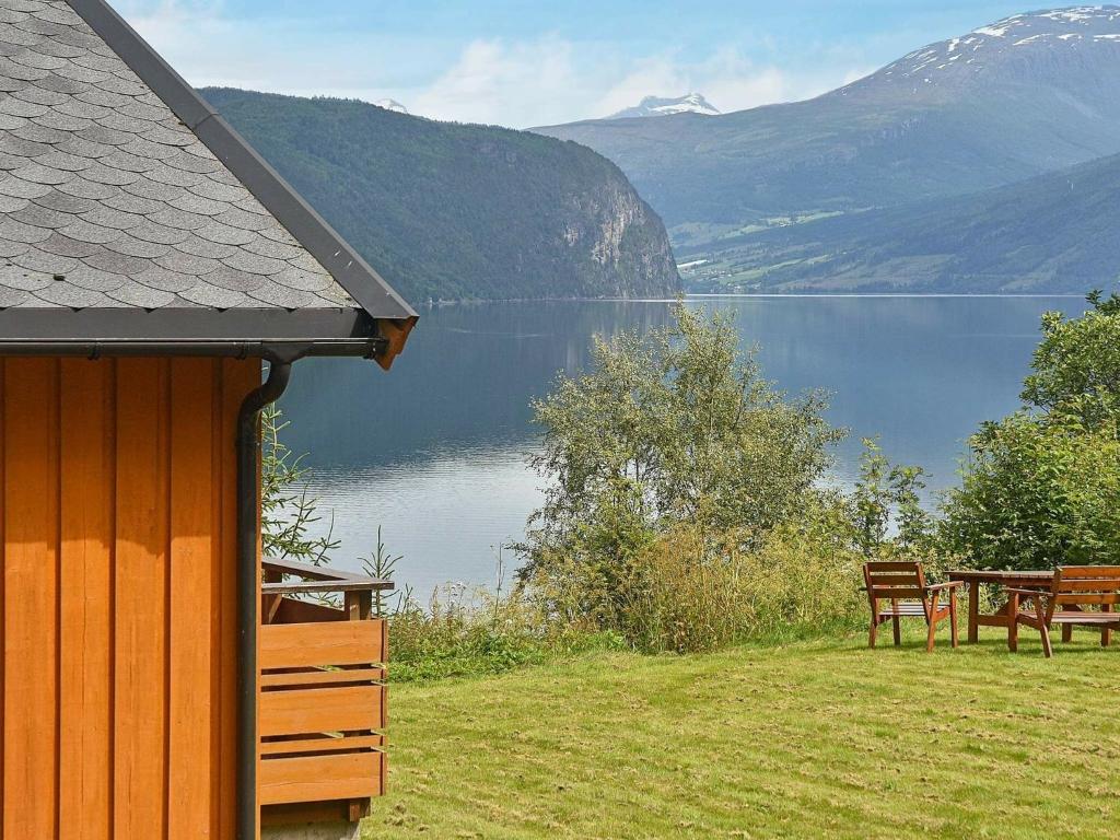 a house with a table and a bench next to a lake at Three-Bedroom Holiday home in Utvik 1 in Reed