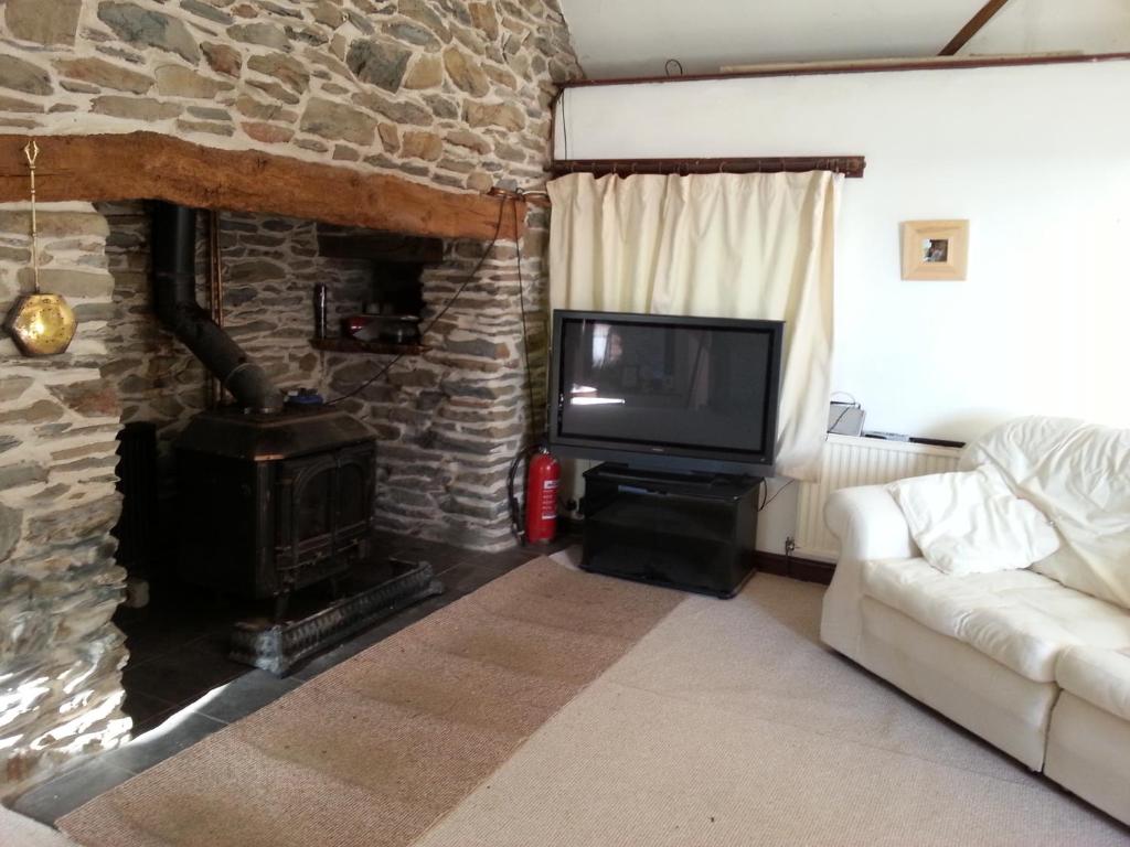 a living room with a stone fireplace and a tv at Horseshoe Pass Holiday Lets in Llangollen