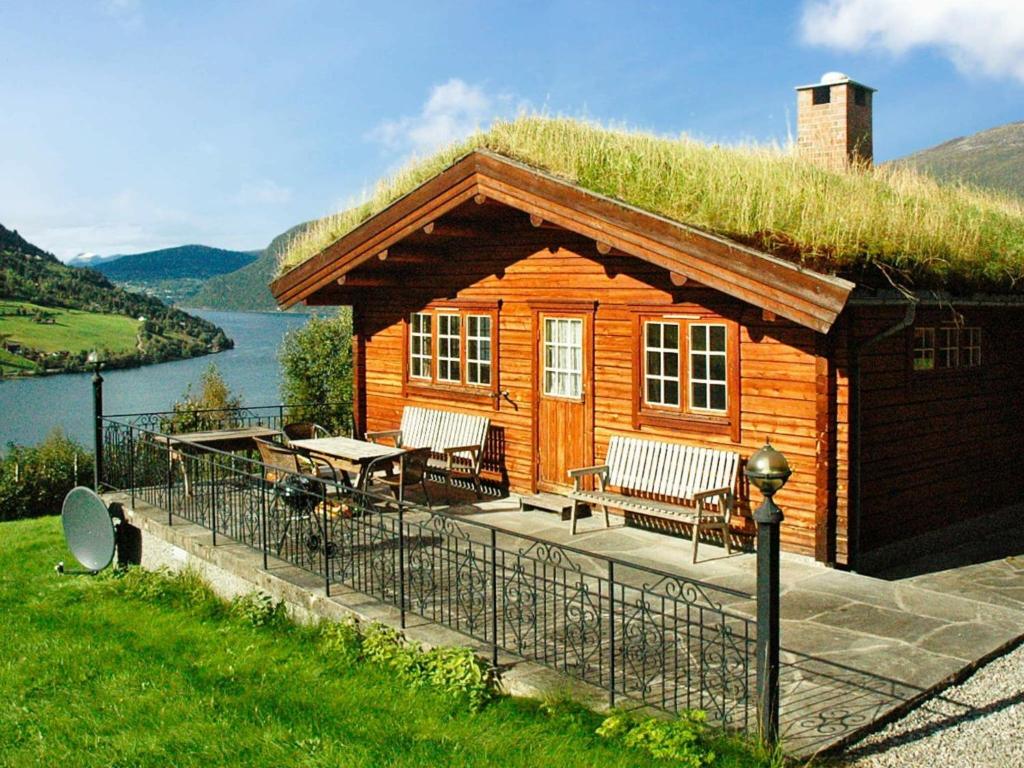 a log cabin with a grass roof with a table and chairs at Four-Bedroom Holiday home in Olden 1 in Olden