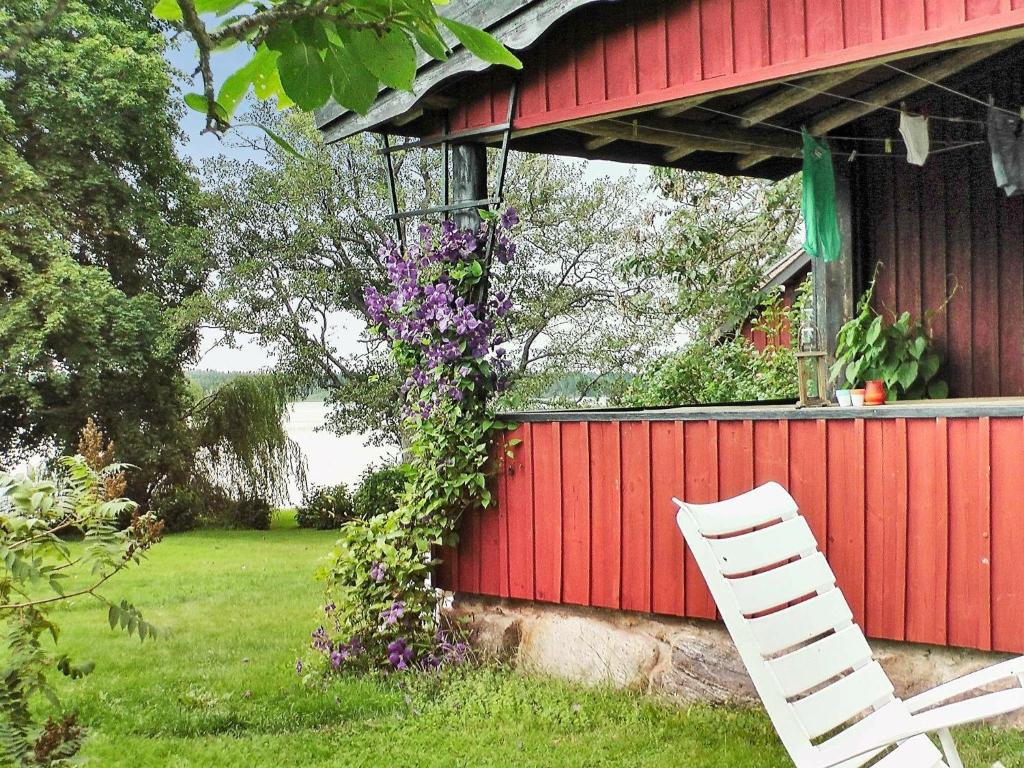 une chaise blanche assise à côté d'un bâtiment rouge orné de fleurs dans l'établissement Two-Bedroom Holiday home in Väddö 1, à Veda