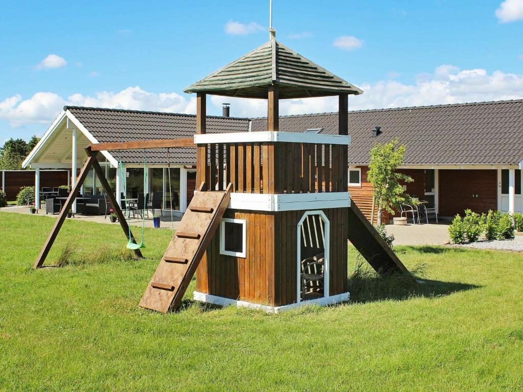 a playground with a slide in the grass at 14 person holiday home in Idestrup in Marielyst