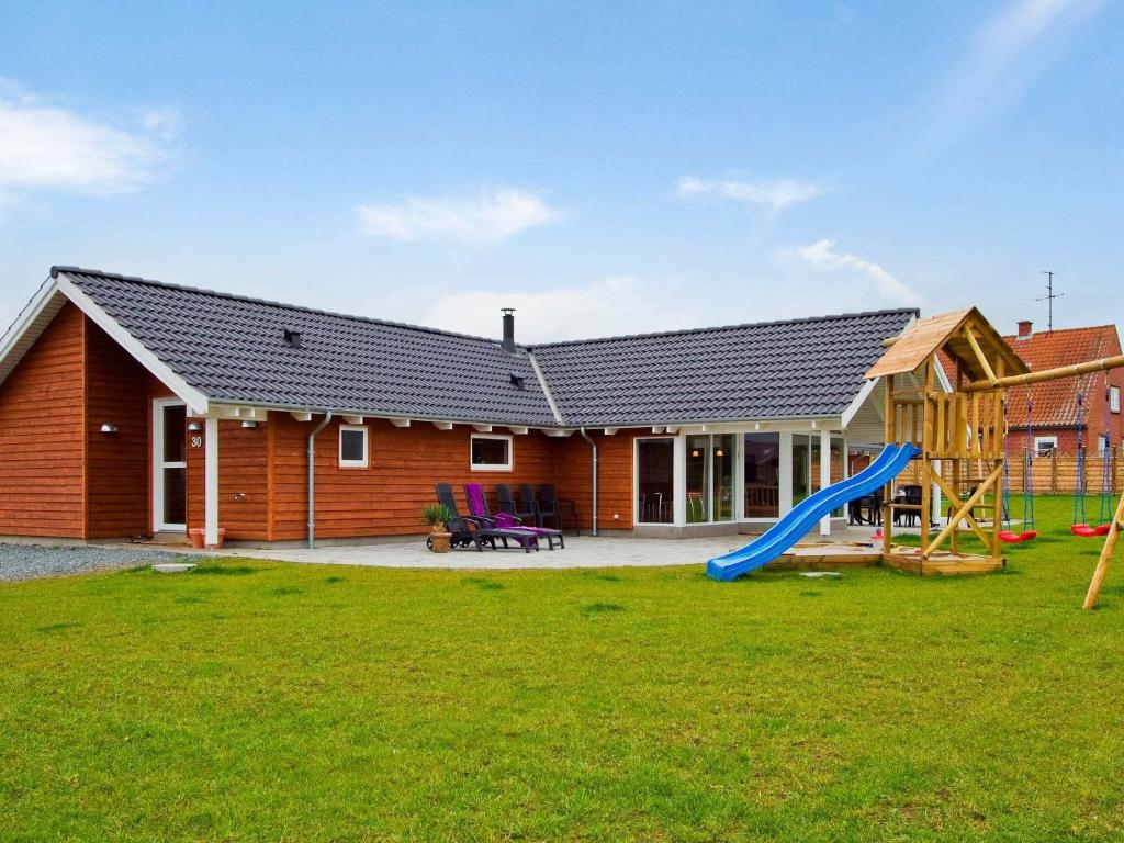uma casa com escorrega e um parque infantil em 14 person holiday home in Sydals em Høruphav