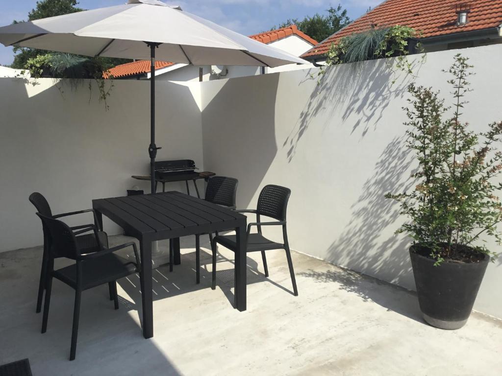 - une table, des chaises et un parasol sur la terrasse dans l'établissement Maison climatisée 47 m2 Biscarrosse proche lac et océan, à Biscarrosse