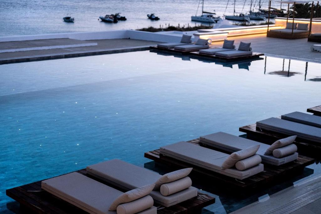 a swimming pool with lounge chairs in the water at Manoula's Beach Mykonos Resort in Agios Ioannis Mykonos