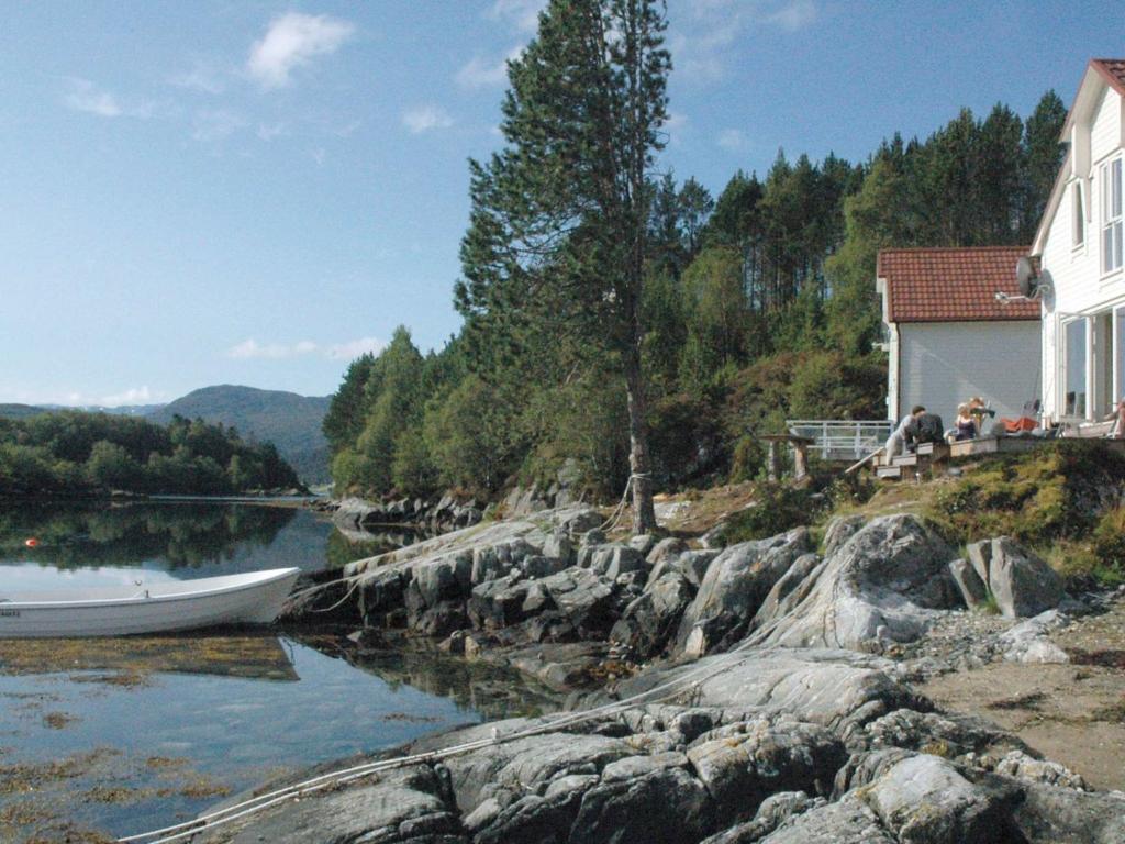 a boat on a river next to a house at Four-Bedroom Holiday home in Gurskøy 1 in Kjellsund