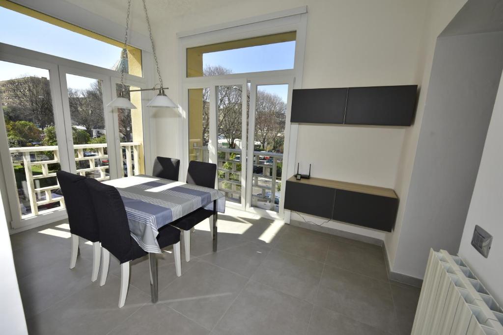 - une salle à manger avec une table, des chaises et des fenêtres dans l'établissement Appartamento appena ristrutturato, à Massa