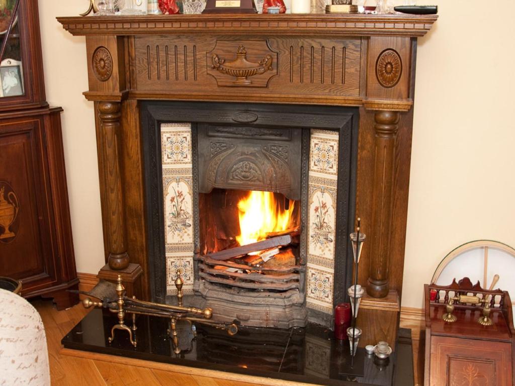 a fireplace in a living room with a fire in it at Rockcrest House in Kenmare