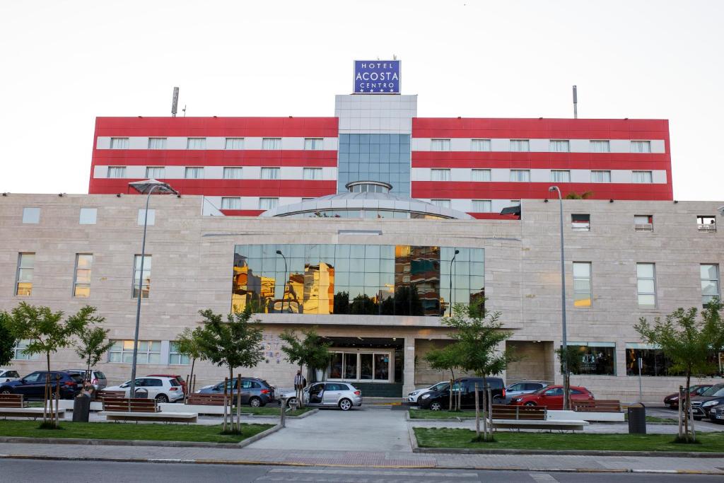 ein großes Gebäude mit Autos auf einem Parkplatz in der Unterkunft Hotel Acosta Centro in Almendralejo