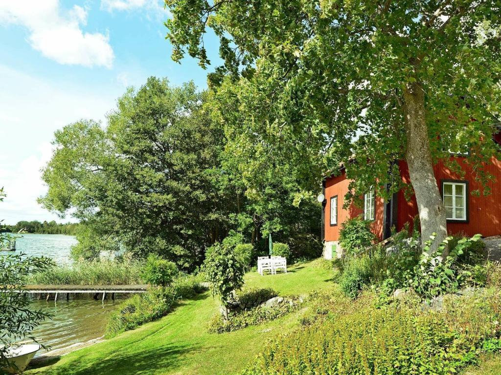 ein rotes Haus auf einem Hügel neben einem Wasserkörper in der Unterkunft 5 person holiday home in MARIEFRED in Mariefred