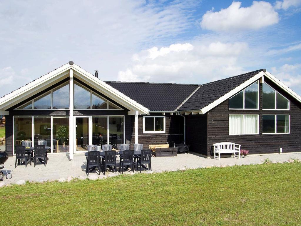 ein Haus mit schwarzen Stühlen, Tischen und Fenstern in der Unterkunft 16 person holiday home in Sydals in Høruphav