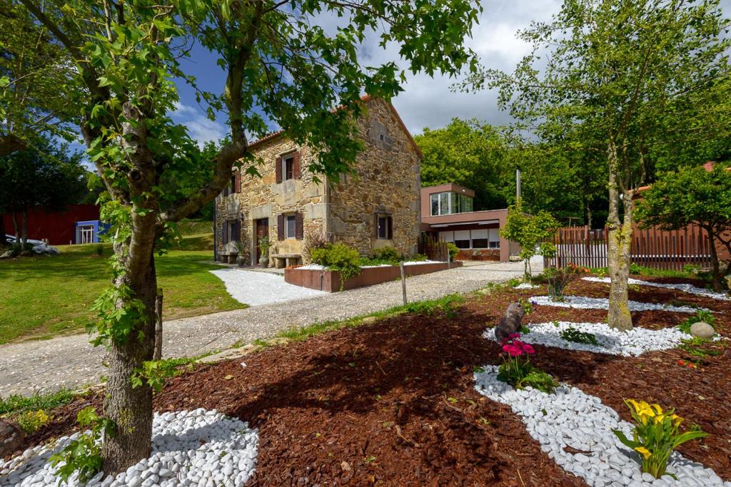 una antigua casa de piedra con un jardín delante de ella en A casa do avo Andres, en Dumbría