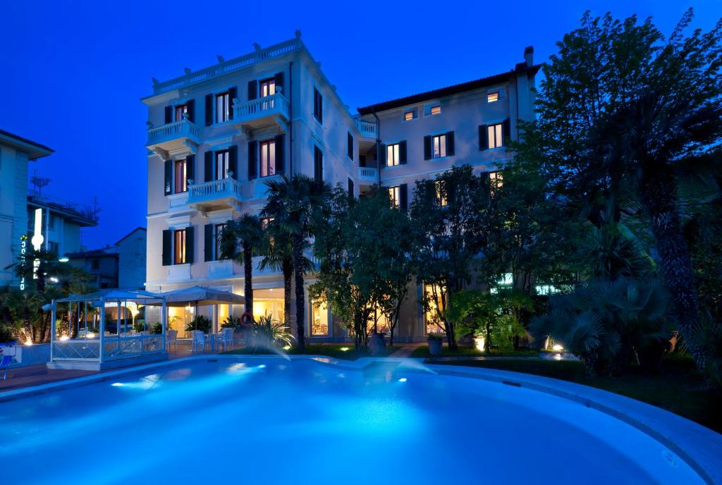 - un bâtiment avec une piscine en face de lui la nuit dans l'établissement Parma E Oriente, à Montecatini Terme