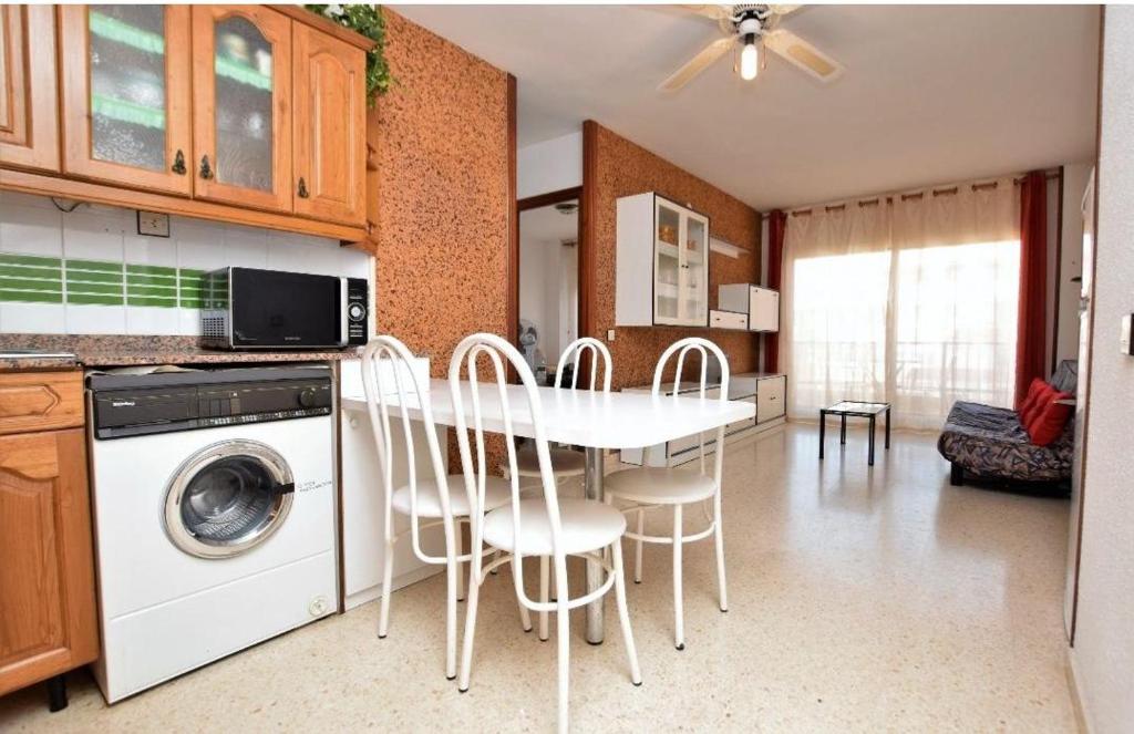 a kitchen with a table and chairs and a washing machine at Apartamento Pineda in Pineda de Mar