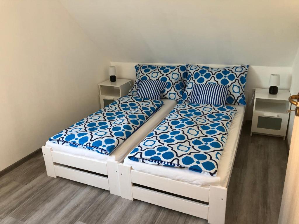 een wit bed met blauwe en witte lakens en kussens bij Marci Apartman in Balatonboglár