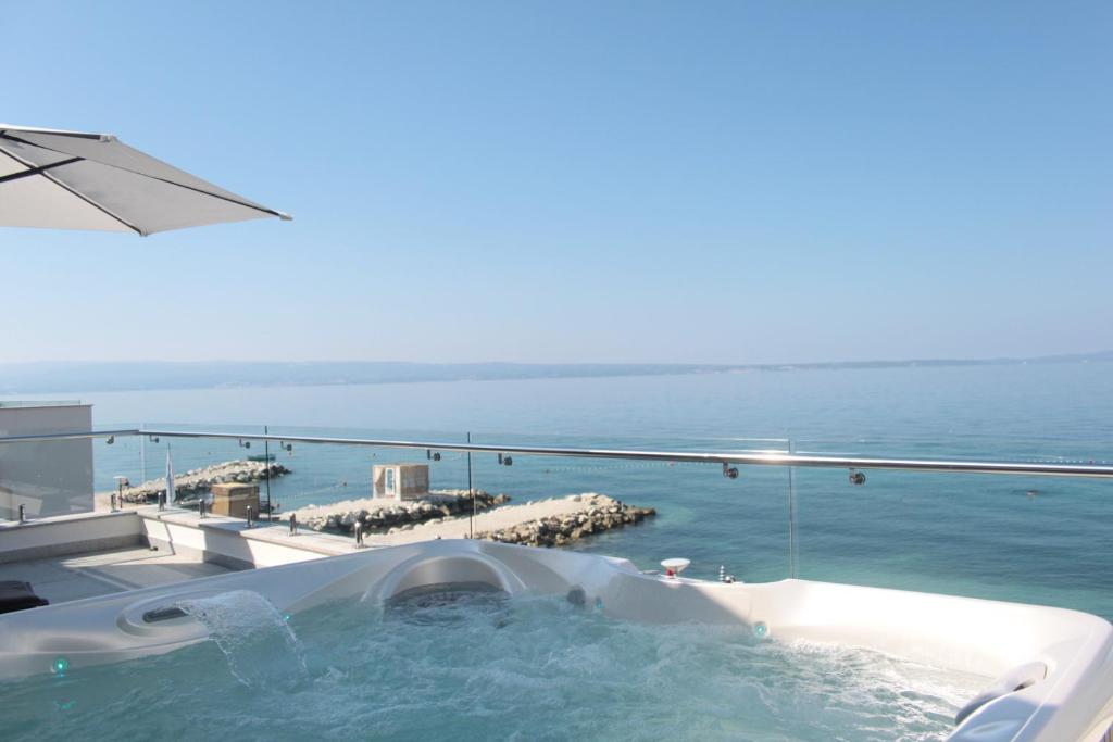 a bath tub on a balcony with a view of the ocean at Beach Hotel Split in Podstrana