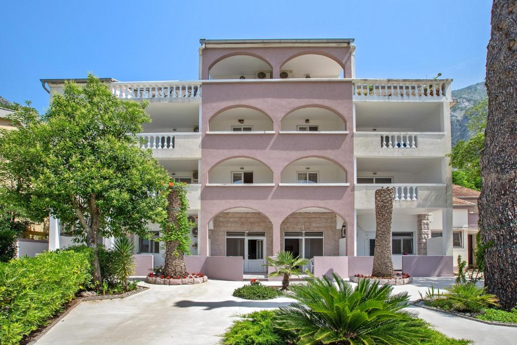 Un edificio rosa con árboles delante. en Apartments Villa Popovic, en Kotor