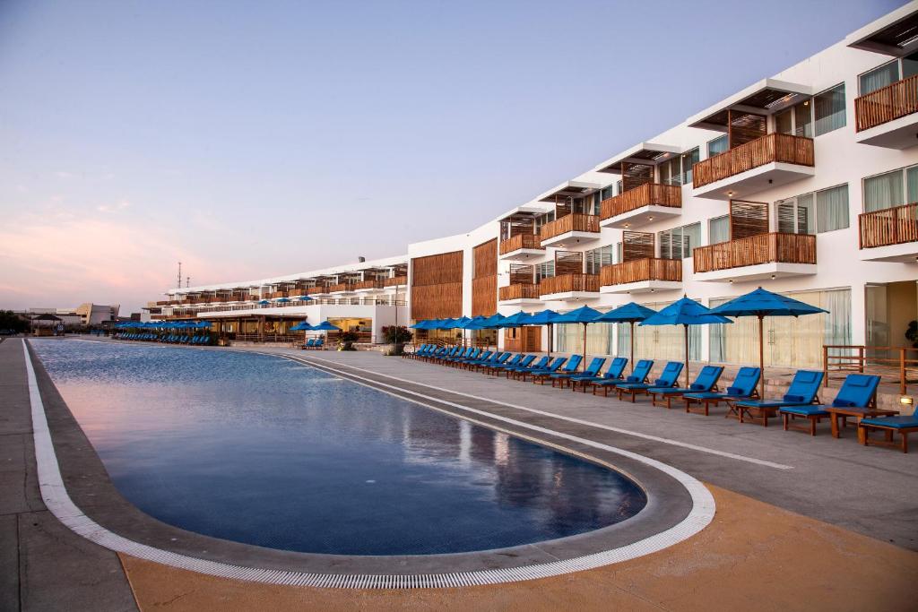un hotel con piscina con sillas y sombrillas en San Agustin Paracas, en Paracas