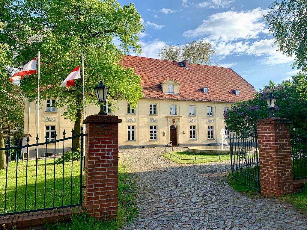 a building with two flags in front of a fence at Schloss Diedersdorf in Diedersdorf