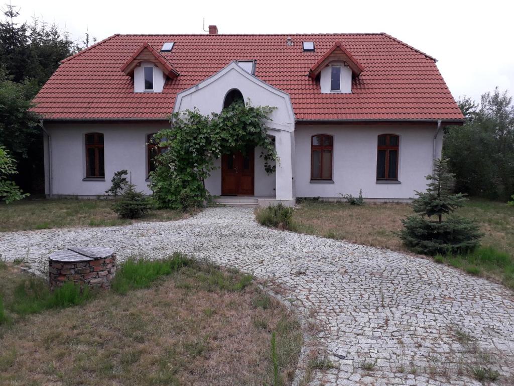 uma casa branca com um telhado vermelho e uma entrada de cascalho em Dworek Cicha Noc em Tarnowo Podgórne