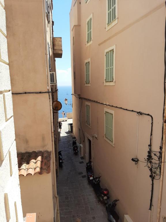 eine Gasse zwischen zwei Gebäuden mit dem Ozean im Hintergrund in der Unterkunft Petit Appart Douillet au Cœur de la Haute-ville in Bonifacio