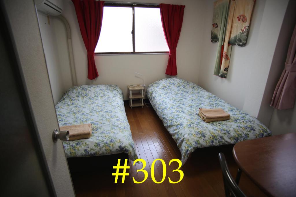 two beds in a small room with a window at マンションロアジス 大阪市東淀川区相川 in Osaka