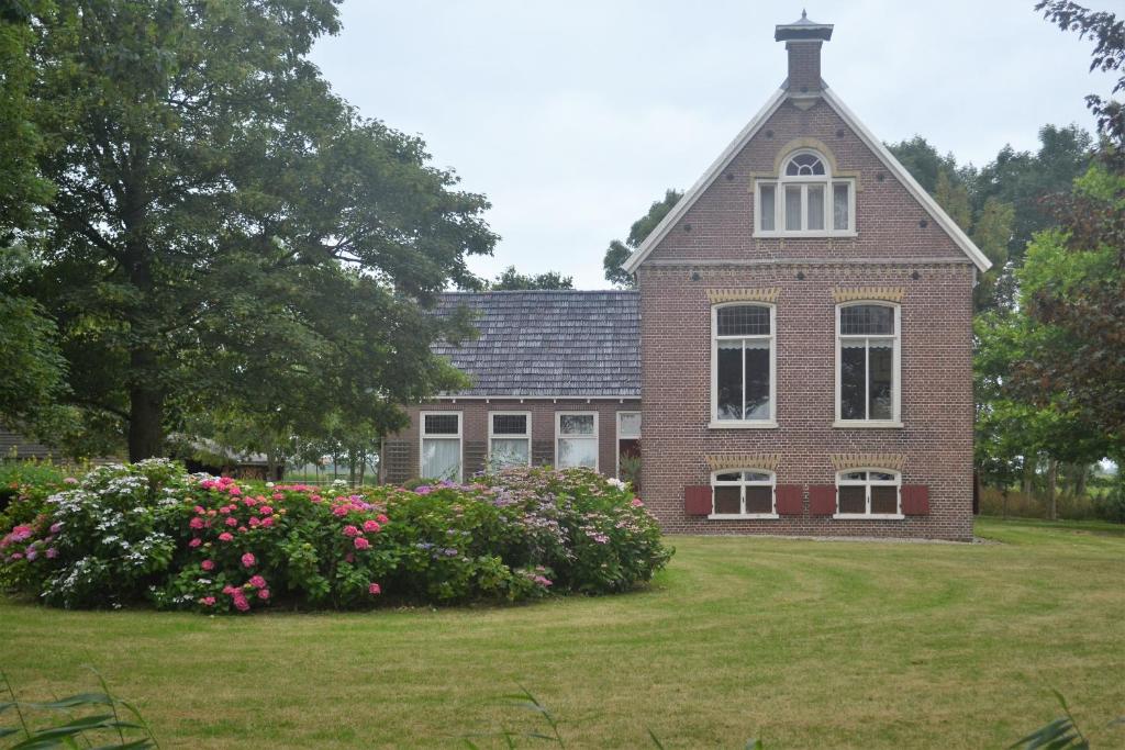 una gran casa de ladrillo con flores delante en Het Friese Huisje, en Boazum