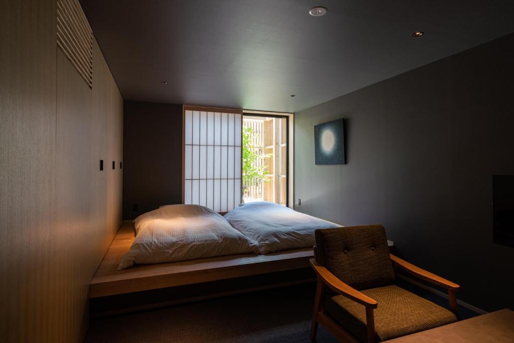 a bedroom with a bed and a chair and a window at Gunjo no Tsuki in Kanazawa