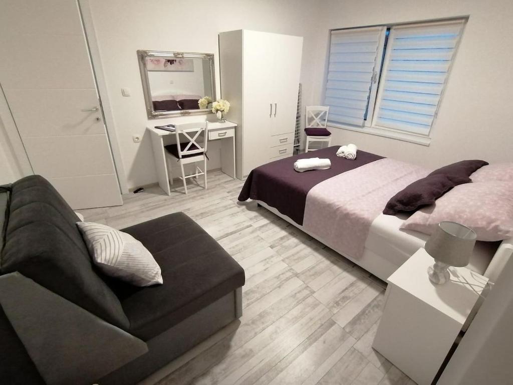 una camera con letto, divano e scrivania di Apartman Lidija a Pag