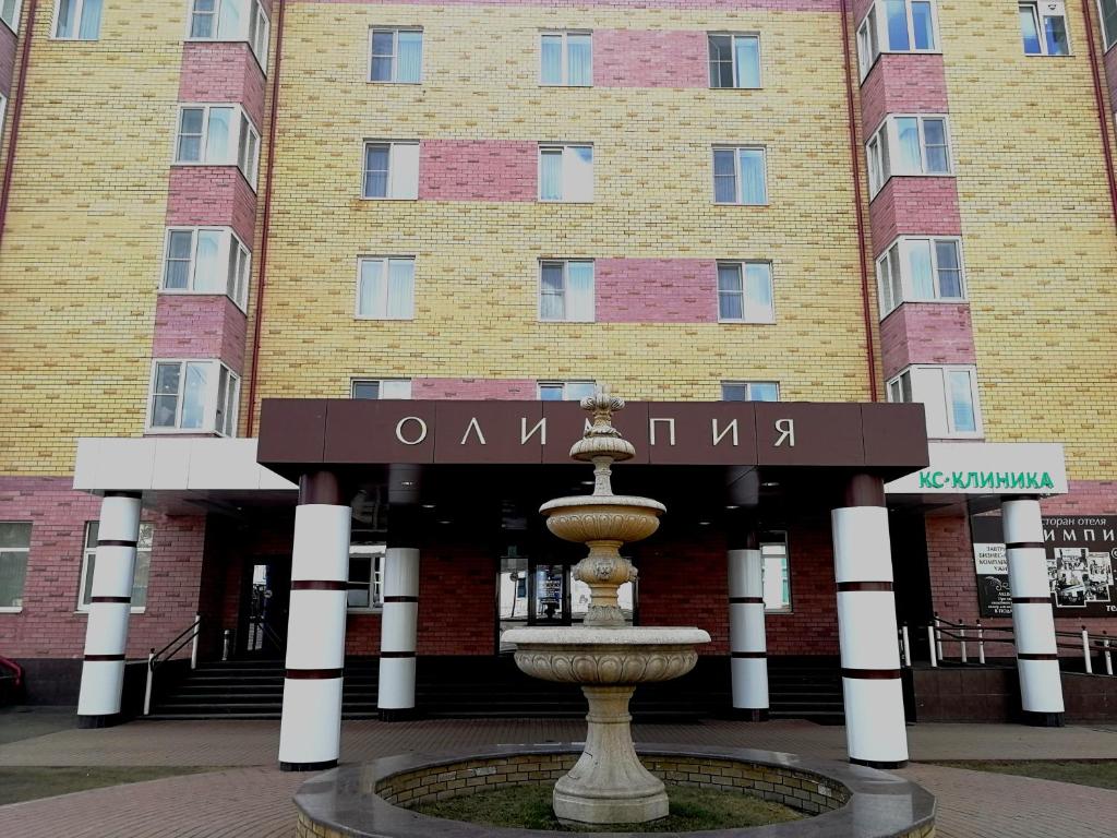 een gebouw met een fontein voor een gebouw bij Hotel Olympia in Saransk