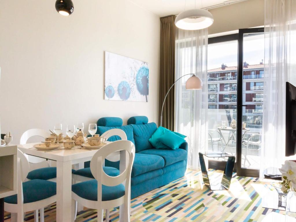 ein Wohnzimmer mit einem blauen Sofa und einem Tisch in der Unterkunft VacationClub – Baltic Park Molo Apartament C104 in Świnoujście