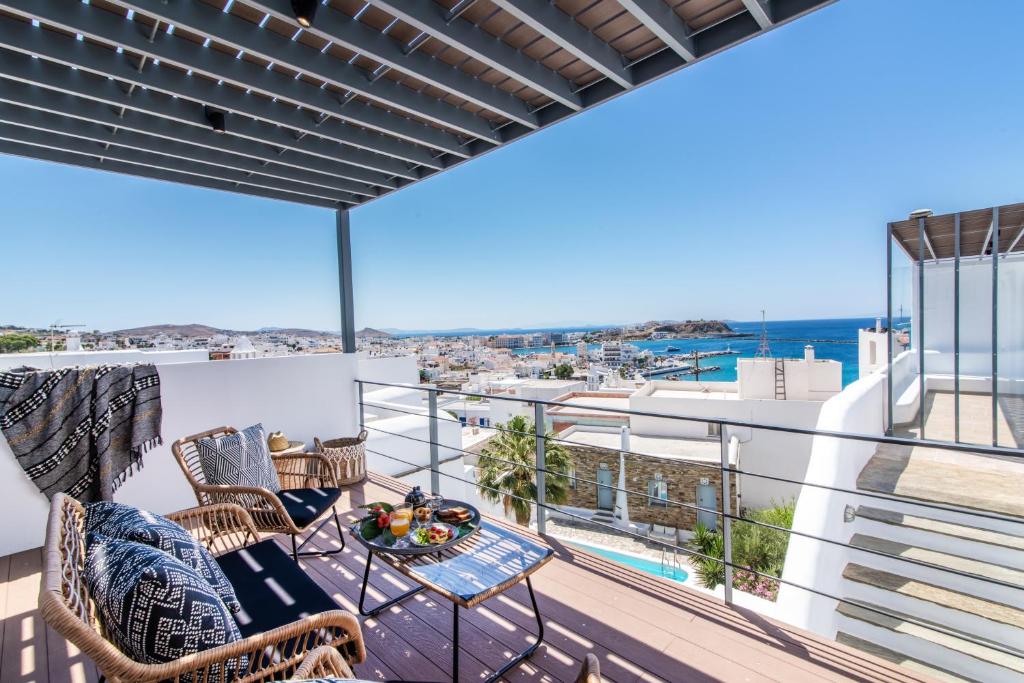 a balcony with chairs and a table and a view of the ocean at Onar Hotel & Suites in Tinos