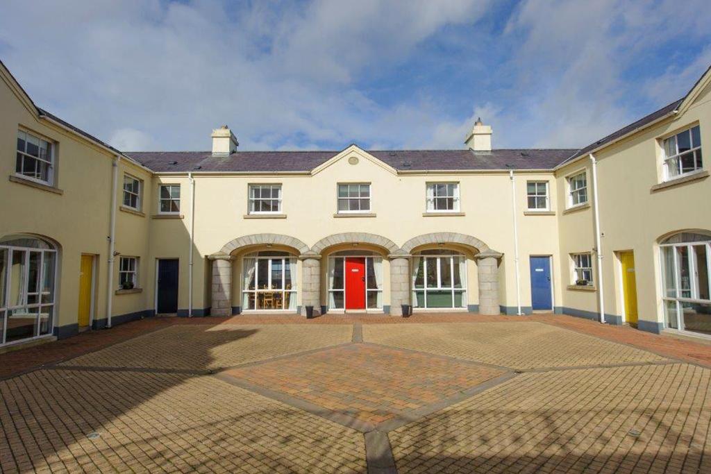 un grande edificio bianco con porte rosse e un cortile di The Downshire Arms Apartments Hilltown a Newry
