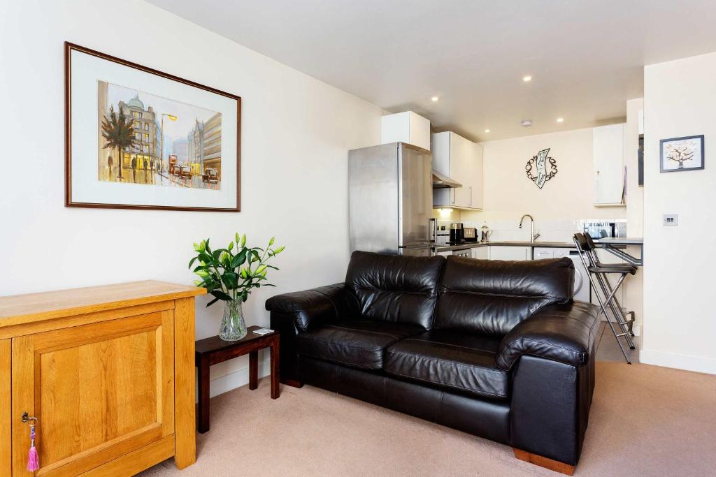 a living room with a leather couch and a kitchen at Veeve - Contemporary by Regent's Canal in London