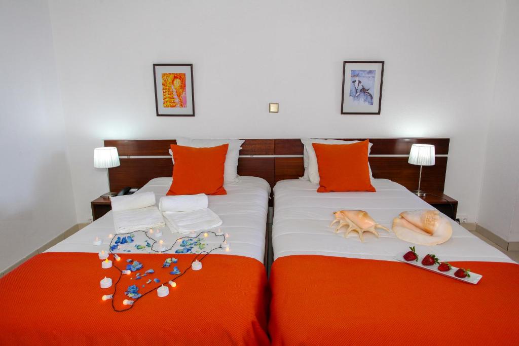 a bedroom with two beds with orange pillows at Aparthotel Barracuda in Ponta Delgada