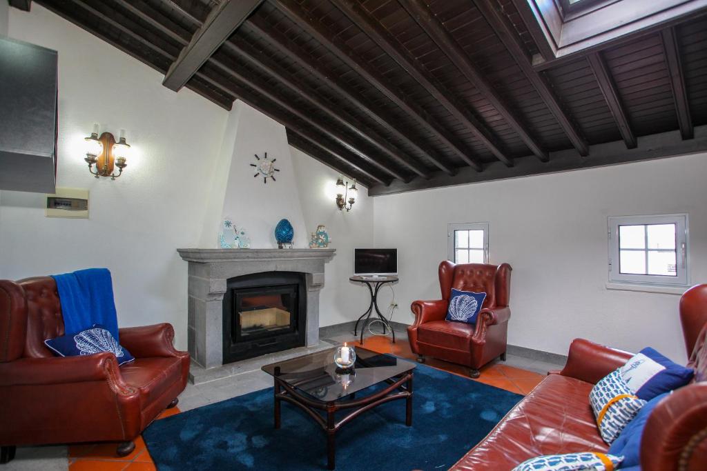 a living room with leather furniture and a fireplace at Aparthotel Barracuda in Ponta Delgada