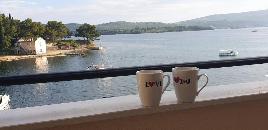 Dos tazas de café sentadas en un alféizar con vistas al lago en Tondo en Tivat