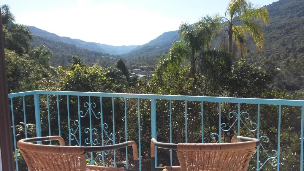 een balkon met 2 stoelen en uitzicht op de bergen bij Pousada Camponesa in Picada Cafe