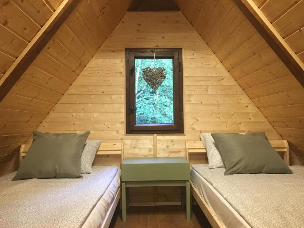 2 camas num quarto no sótão com uma janela em Erdő Kapitánya Vendégház em Tata