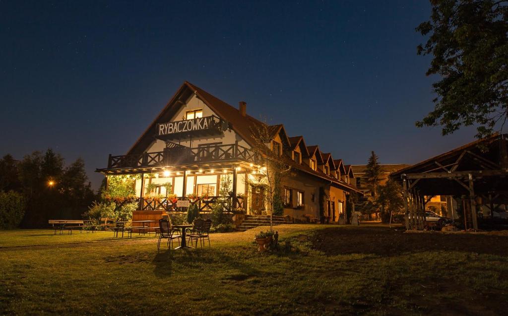 un gran edificio con luces encendidas por la noche en Pensjonat Rybaczówka, en Giżycko