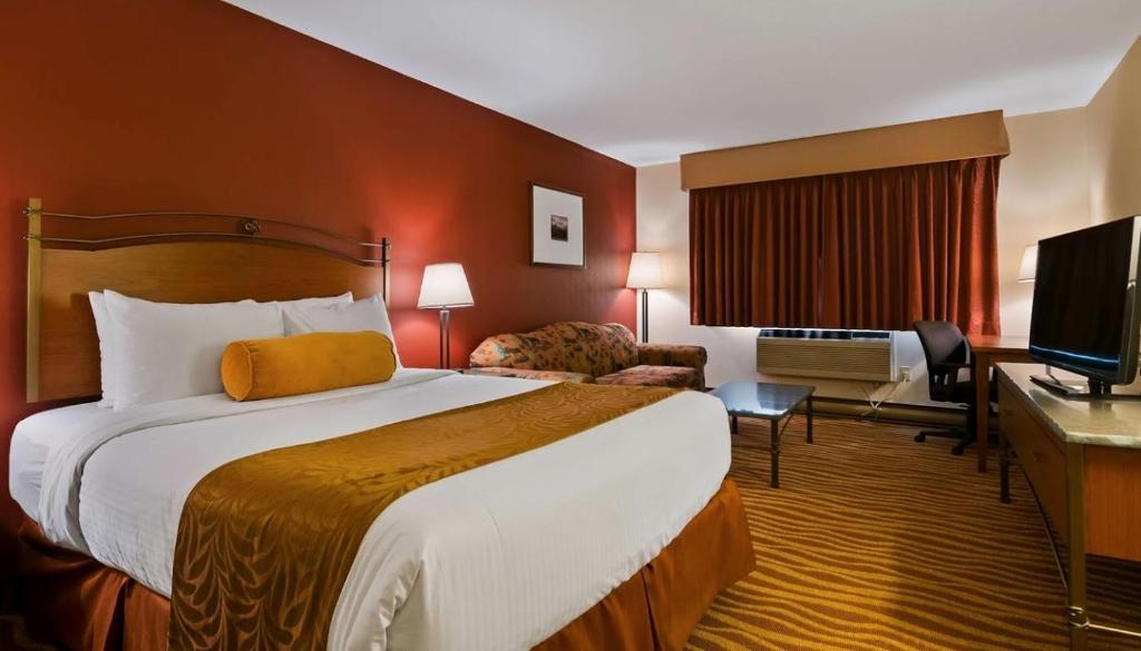 um quarto de hotel com uma cama grande e uma televisão em Invermere Inn & Suites em Invermere