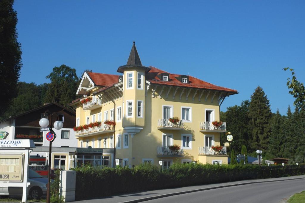 ein großes gelbes Gebäude mit rotem Dach in der Unterkunft Hotel Das Schlössl in Bad Tölz