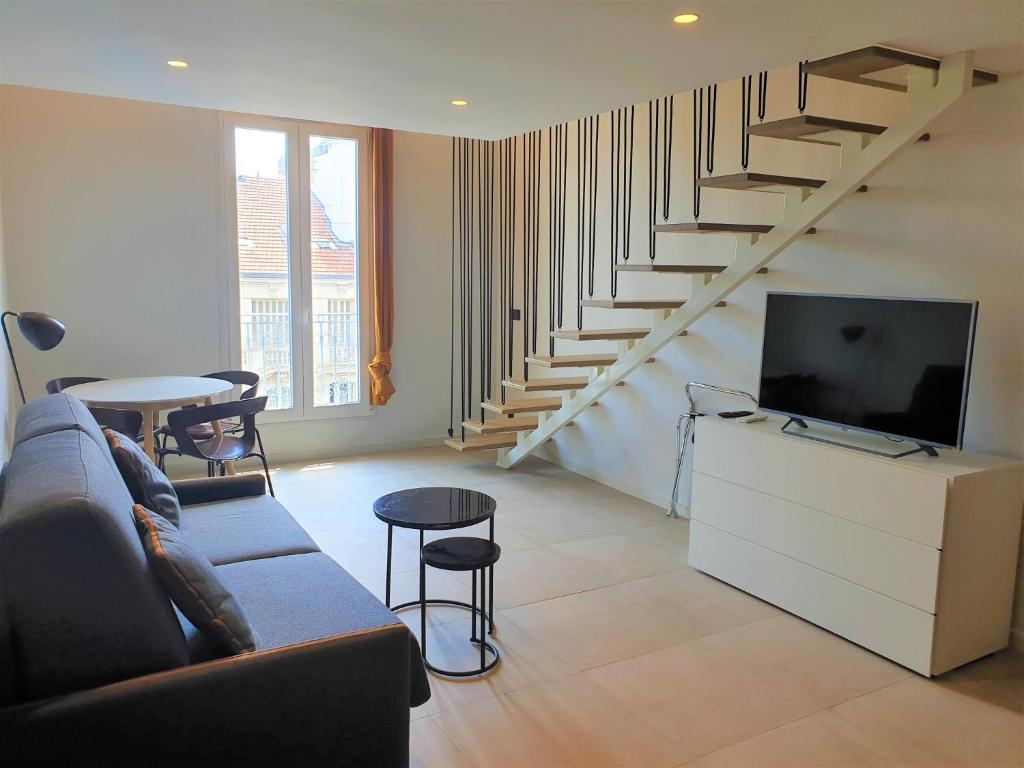 - un salon avec un canapé, une télévision et des escaliers dans l'établissement DUPLEX CENTRE MER 505, à Nice