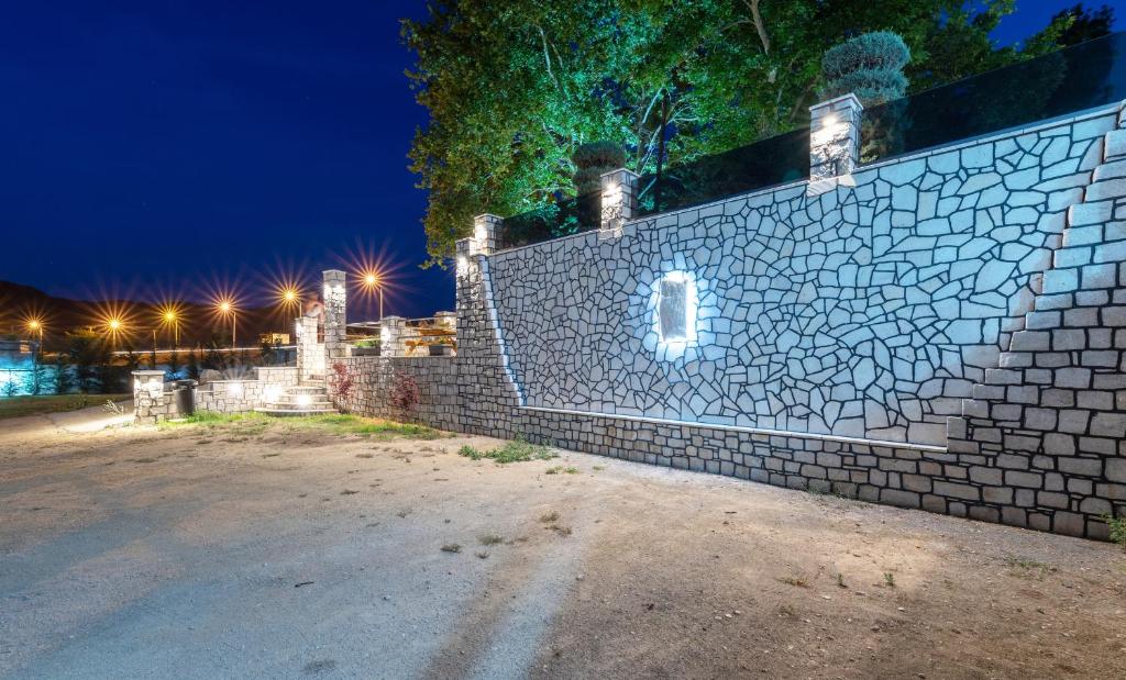 a brick fence with lights on it at night at A Ponte Studios & Apartments in Sykia Chalkidikis